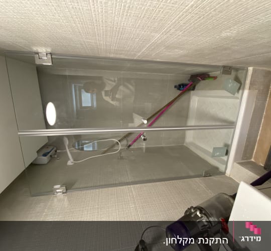 מקלחון עם דלת זכוכית ומקלחת יד